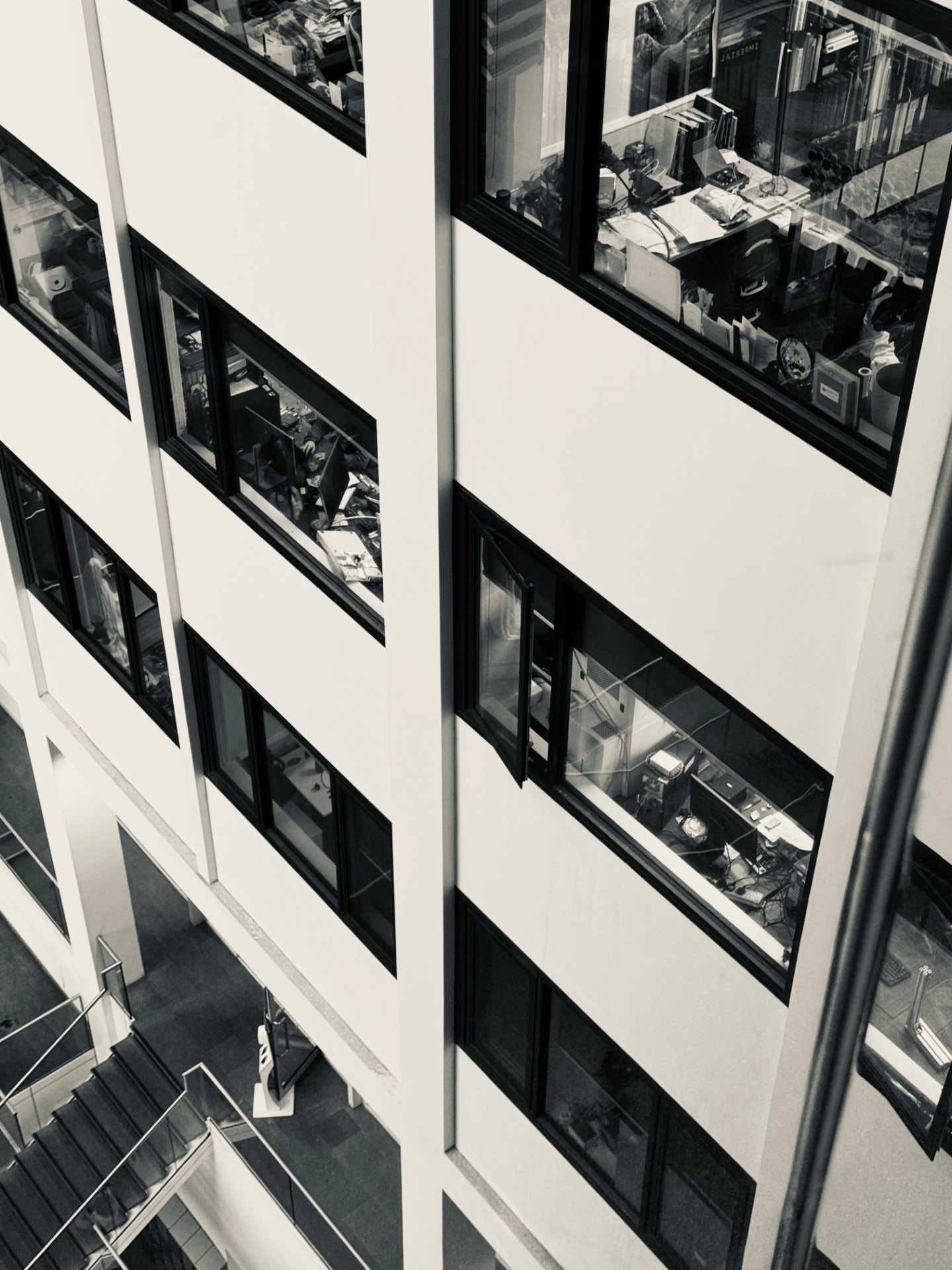 Black and white view of a modern office building facade with working offices behind glass